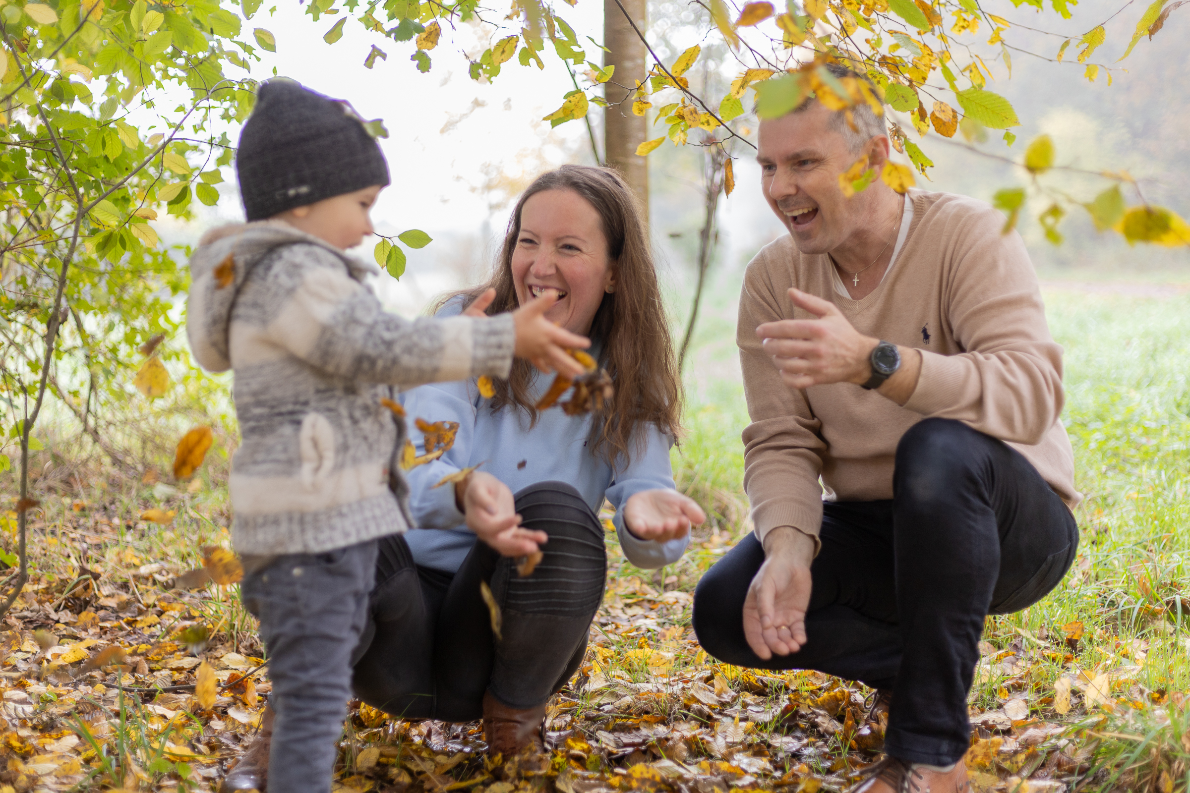 Familie im Wald, Herbstlaub wird geworfen und alle lachen