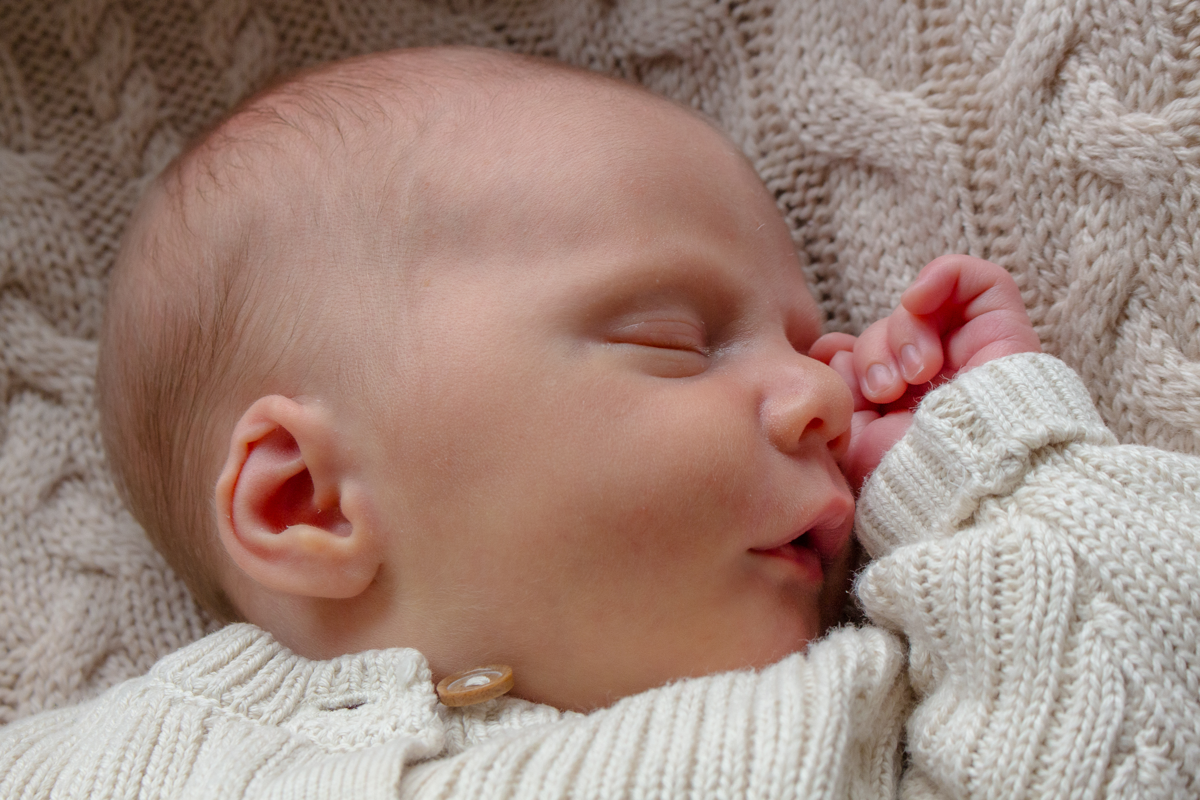 Neugeborenes Baby liegt auf einer Wolldecke und schläft